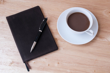 notebook and coffee cup on wooden table