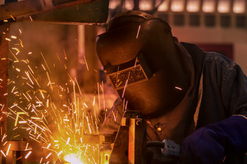 Worker is welding steel part in  factory