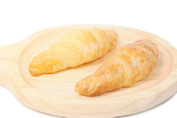 Double croissants on wooden plate with light flare