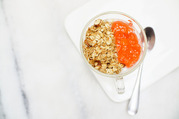 Granola yogurt with strawberry jam cup on marble table