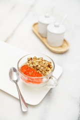 Granola yogurt with strawberry jam cup on marble table