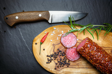 dried salami crusted in ground red pepper on dark background