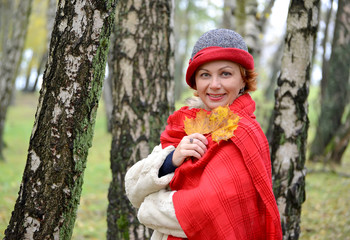 The woman of average years in a hat and a red stole in the birch