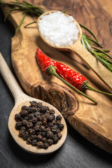 Chili with black pepper and salt on rustic wooden table.