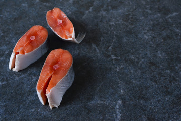 Fresh raw salmon steak on black marble background
