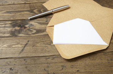 An open brown envelope with letter and writing pen on a rustic wooden background