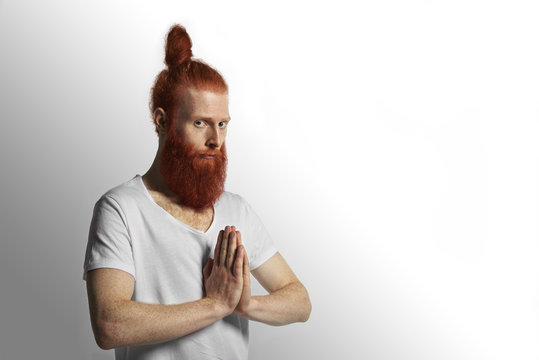 Red beard man praying with hands together in front of chest. Amazing and attractive yoga person preparing for new happy life. The image of a vegetarian