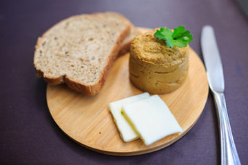 Serve beef pate with a piece of butter and bread on a wooden board, decorated with parsley