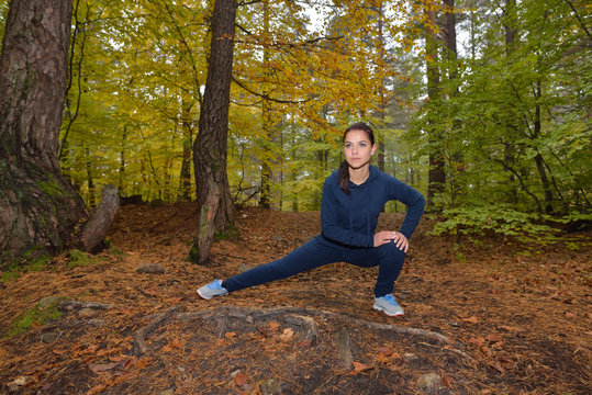 Energetic young woman do exercises outdoors in park to keep their bodies in shape. Fitness concept. Body-building theme. Sport mood.