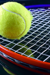 Closeup of  tennis racket with a tennis ball on black background. 