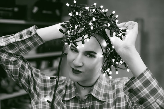 portrait of a beautiful young woman who wears on his head the Christmas lights, instead of a hat