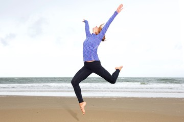 Obraz premium Athletic woman leaping in air with arms outstretched