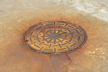 Rusty manhole cover on street, drain cover top view.