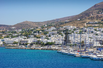 Fototapeta na wymiar Sailing boats are docked on the coast of a small town of white houses, greek islands in the sunny day of summer