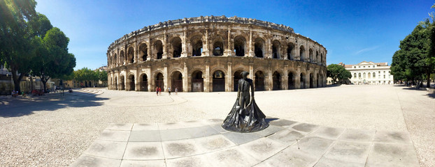 The Roman amphitheater (Roman Arena) and bullfighter statue in Nimes, France.