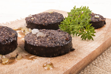 grilled irish black pudding with parsley on a wooden board