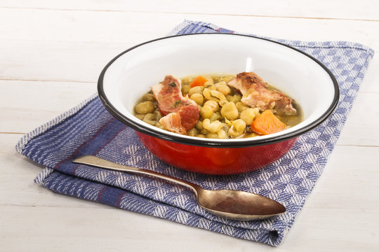 peas soup with carrots and pork meat in an enamel bowl