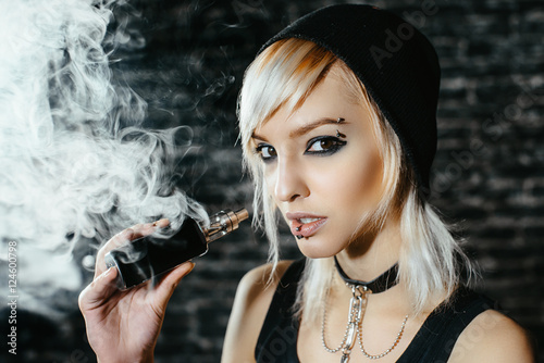  Sexy goth girl smokes electronic cigarette on dark 