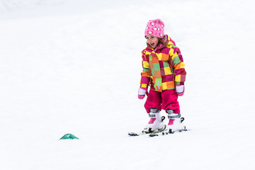 Fototapeta na wymiar Little girl is learning to ski in ski resort.