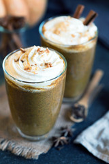 Two glass cups of pumpkin latte topped with whipped cream walnut