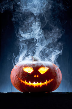 Halloween pumpkin in moonlight and smoke on the table