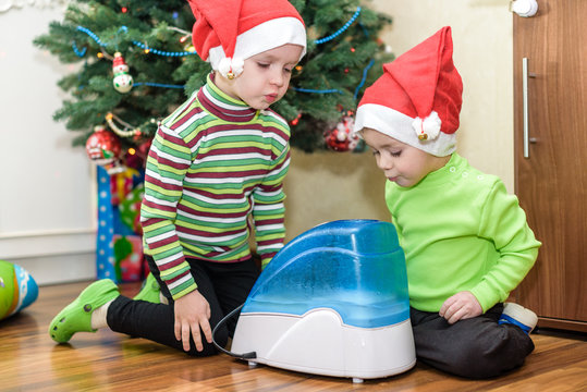 two adorable boys playing with working humidifier, waiting for x-mas