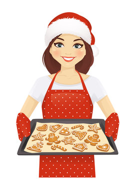 Smiling woman holding baking tray with christmas cookies wearing santa hat isolated