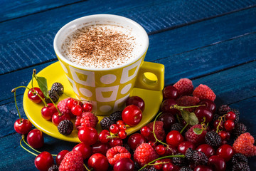 Coffee cup decorated with berries on the navy-blue background
