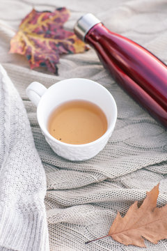Warm knitted sweater,cup of hot tea and red thermos