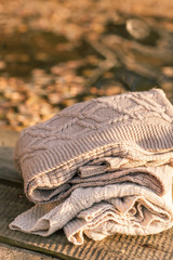 Pile of knitted winter clothes on wooden background, sweaters, k