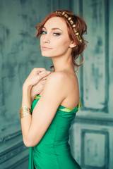 Woman in green evening gown stands in the fashion studio looking on us
