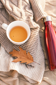 Warm knitted sweater,cup of hot tea and red thermos