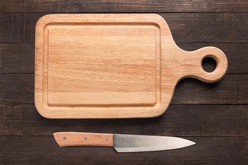 Knife and cutting board on the wooden background. Copy space for your text.