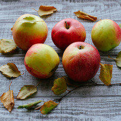 apples on autumn leaves on wooden background