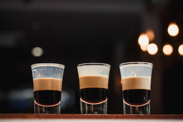 Three layered shots on a bar counter and bokeh background.