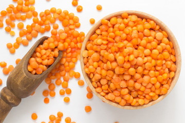 Red lentils in a wooden bowl on a white