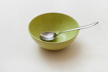 green bowl with spoon on white plaster
