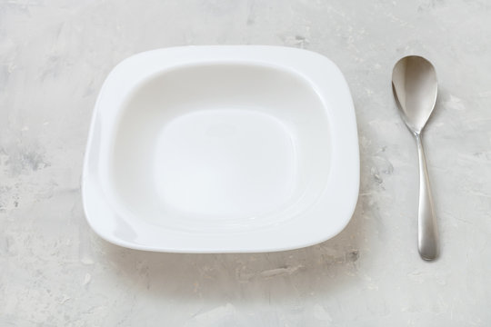 square white bowl and spoon on gray concrete