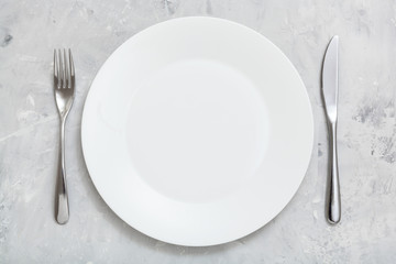 top view white plate with knife, spoon on concrete