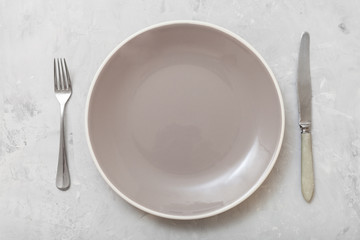 top view gray plate with knife, spoon on concrete
