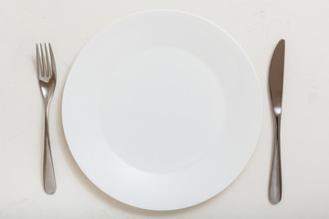 top view of white plate with knife, spoon on white