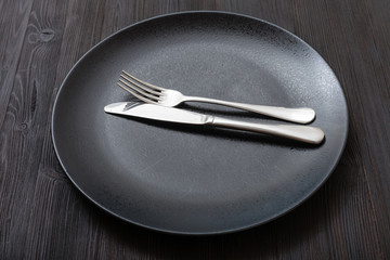 black plate with parallel knife, spoon on dark