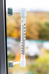 outdoor thermometer on home window glass in autumn