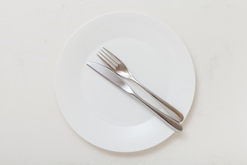 top view of white plate with flatware on white