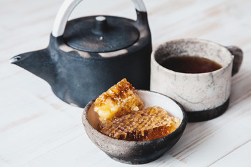 Old ceramic teapot with a Cup of tea and biscuits in a bowl on wooden background