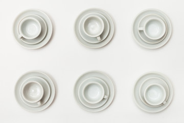 top view of six white cups and saucers on white