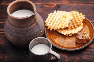 Beautiful vintage ceramic jug with milk and honeycomb on brown wooden background