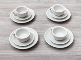 four white cups and saucers on gray brown table