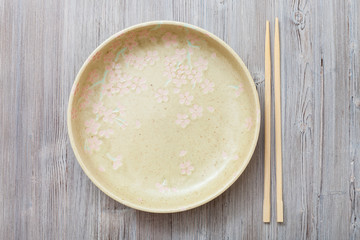 top view of yellow plate and chopsticks on gray