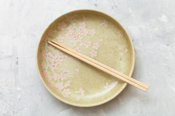 top view yellow plate with chopsticks on concrete